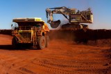 An earth mover shifts dirt into a truck in the Pilbara