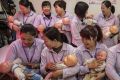 Chinese women hold plastic babies at the Ayi University which teaches childcare, early education in preparation for ...