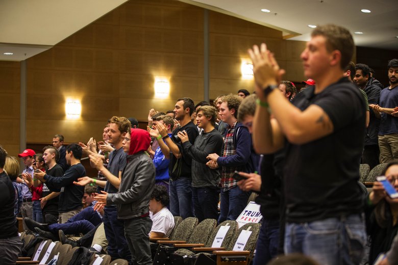 The assembled audience at Kane Hall rises to a standing ovation after Milo Yiannopoulos says he intends to continue his speech despite word that someone had been shot outside the auditorium. (Dean Rutz/The Seattle Times)