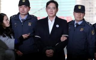Jay Y Lee, vice chairman of Samsung, is escorted by police officers as he arrives for questioning in Seoul