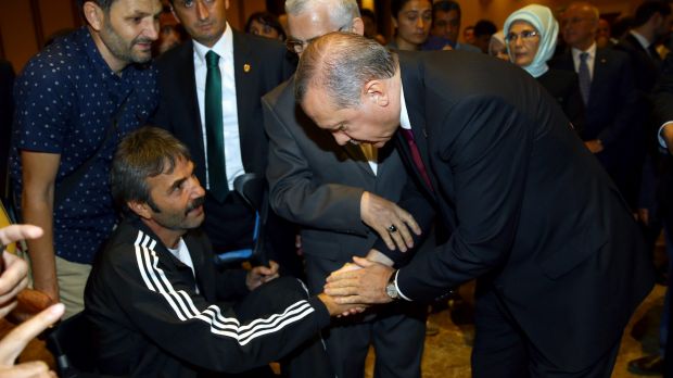 Mr Erdogan, right, shakes hands with a wounded civilian during an event to honour those killed and wounded during the ...