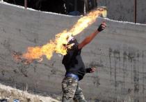 A Palestinian protester throws a Molotov cocktail towards Israeli security forces 