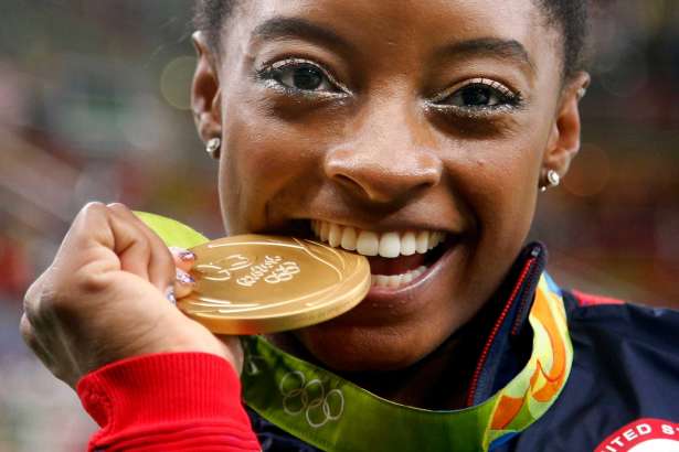 In this Aug. 11, file photo, United States' Simone Biles bites her gold medal for the artistic gymnastics women's individual all-around final at the 2016 Summer Olympics in Rio de Janeiro, Brazil. Biles was selected as the AP Female Athlete of the Year on Dec. 26.