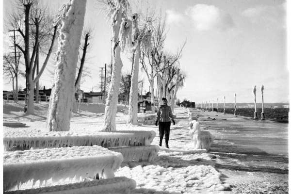 "Record low temperatures and heavy snow plagued the Seattle area during the winter of 1950. On Friday January 13, downtown Seattle received an average of ten inches of snow, with Sea-Tac airport reporting 21.4 inches, just shy of a 24-hour snowfall record. Although the snow let up on Saturday, the cold temperatures persisted for several more days. Seattle recorded nine days of temperatures below ten degrees between January 12 and February 4, 1950. In this photo, a woman poses on the frozen parkway next to Alki Beach in West Seattle." -MOHAI. Photo courtesy MOHAI, Seattle P-I Collection, image number 1986.5.14562.