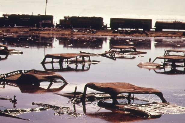 Original caption: &nbsp;A train on the Southern Pacific Railroad passes a five-acre pond, which was used as a dump site by area commercial firms, near Ogden, Utah, in April of 1974. The acid water, oil, acid clay sludge, dead animals, junked cars and other dump debris were cleaned up by several governmental groups under the supervision of the EPA. Some 1,200,000 gallons of liquid were pumped from the site, neutralized and taken to a disposal site. 
  Date:&nbsp; April, 1974.