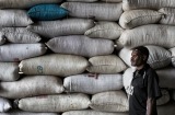 A worker in front of sacks of coffee, its glory days long gone.