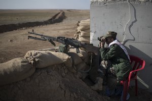 A Kurdish Peshmerga soldier observes Islamic State-held territory through binoculars at a frontline position near Khorsabad, north of Mosul, Iraq, Wednesday, Nov. 2, 2016