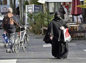 A veiled Muslim woman with a shopping bag walks in the city of Bonn, Germany, Tuesday, Jan. 12, 2016.