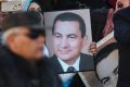 A small number of supporters of ousted former Egyptian President Hosni Mubarak hold posters with his photo, as they ...