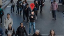 A man stands still on his phone in a crowd as people move around him.