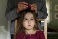 A young girl being treated for head lice.