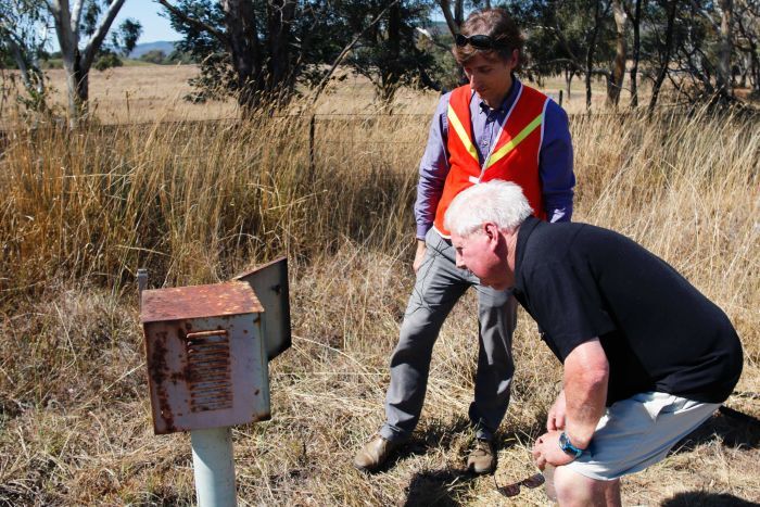 A member of the public, accompanied by a Roads ACT staff member, looks inside a roadside metal box.