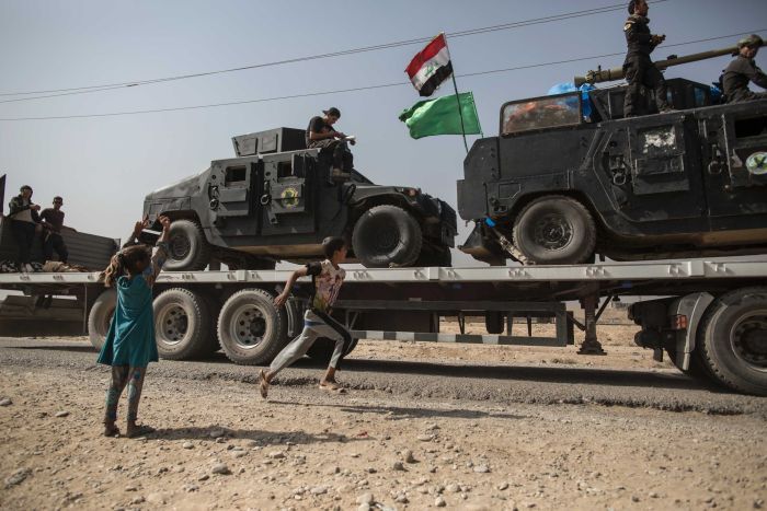 Children run alongside military vehicles in Imam Gharbi, near Mosul