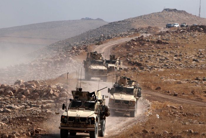 A convoy of armoured vehicles drive in Naweran, Iraq