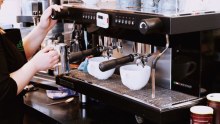 Barista warms milk at industrial coffee machine