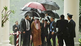 Saudi King Salman and Indonesian President Joko Widodo walk under umbrellas in heavy rain