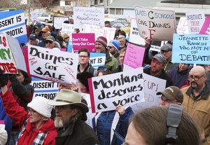 Protesters wave signs as they listen to speakers outside the Montana Capitol in Helena on Tuesday, Feb. 21, 2017.