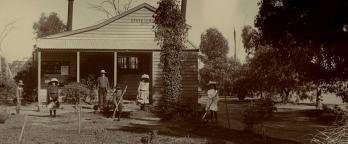 Black and white photo of people in front of farmhouse