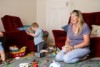 Family day care provider Alvina Brooks in the lounge room with one child in the background playing with a toy. 