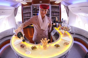 Cabin crew serve champagne in the onboard lounge on an Emirates A380.