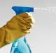 Human hand wearing rubber glove and holding spray bottle