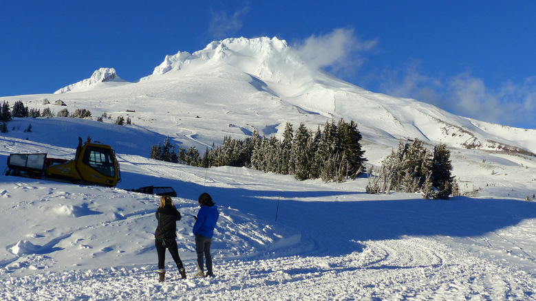 Visitors from Vancouver, Wash., take a photo as evening sun lights Oregon’s Mount Hood from outside Timberline Lodge. (Brian J. Cantwell / The Seattle Times)