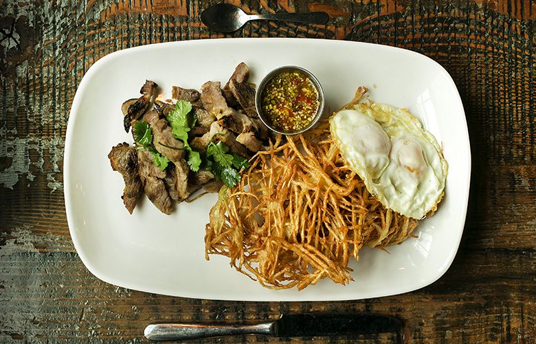 Pork Collar and Eggs (grilled pork collar rubbed with coriander root, garlic, and pepper, glazed with soy sauce and palm sugar, grilled, two eggs, hand cut fried papaya and spicy lime sauce) as prepared at Soi on Saturday, February 25, 2017, in the Capitol Hill neighborhood of Seattle.