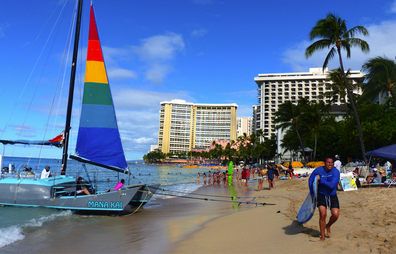 Surfers and sailboats crowd popular Waikiki Beach. 