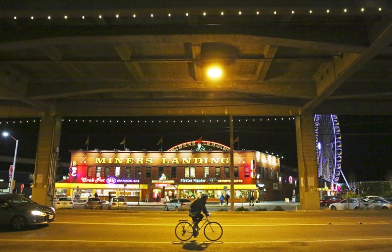 A cyclist rides near the Seattle Great Wheel underneath the gigantic vaulting of the Viaduct’s lower deck. (Ken Lambert/The Seattle Times)