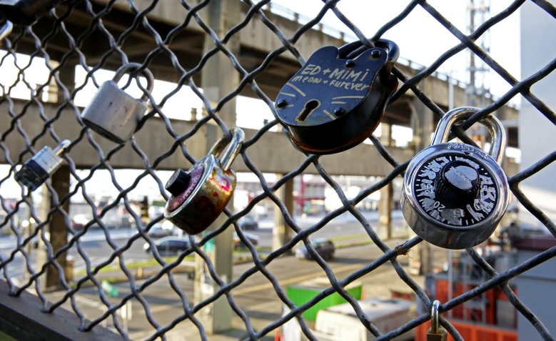 A collection of locks, many to celebrate relationships, hangs on a fence near the Viaduct’s pedestrian tunnel leading to the Colman Dock ferry terminal. (Ken Lambert/The Seattle Times)