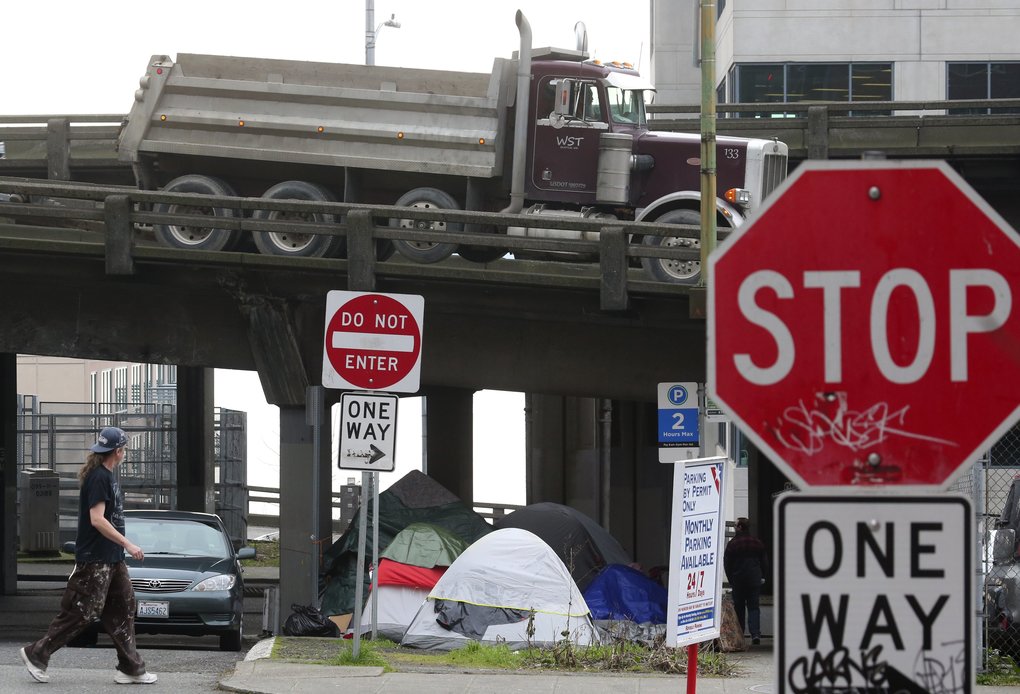 A pedestrian passes a homeless encampment underneath the Viaduct. (Ken Lambert/The Seattle Times)