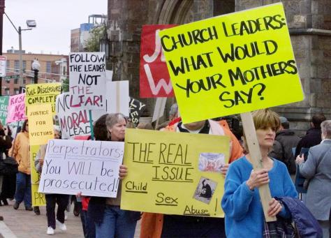 Suzy Nauman (R) of Arlington, Massachusetts leads the way as protesters demonstrate about the clergy child sex abuse scandal in the Boston Archdiocese outside Cardinal Bernard Law's Sunday Mass at the Cathedral of the Holy Cross in Boston, on Mother's Day, May 12, 2002. Law faces a third day of questioning May 13 in a lawsuit brought by alleged victims of convicted pedophile priest John Geoghan over Law's handling of child sexual abuse allegations. REUTERS/Jim Bourg - RTR52F7