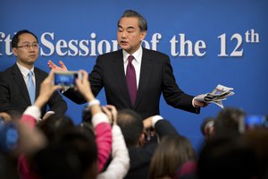 Chinese Foreign Minister Wang Yi gestures as he leaves following a press conference held on the sideline of the National People's Congress at the media center in Beijing, Wednesday, March 8, 2017.