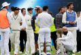 Players and officials wait on the field after the main grandstand and public viewing areas were cleared by security staff .