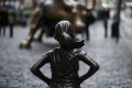 A statue of a defiant girl stands facing the Charging Bull sculpture in the Financial District of New York, U.S., on ...