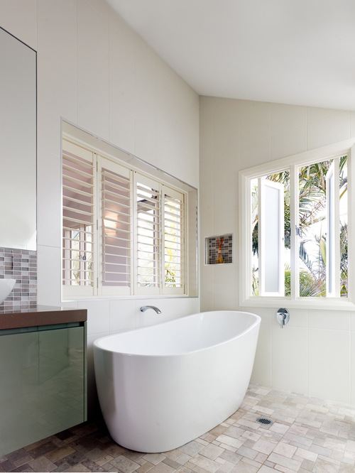 This is an example of a mid-sized contemporary bathroom in Sydney with a vessel sink, flat-panel cabinets, green cabinets, engineered quartz benchtops, a freestanding tub, a corner shower, a one-piece toilet, white tile, glass tile and white walls.