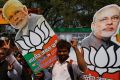 Bharatiya Janata Party supporters raise cutouts of Indian Prime Minister Narendra Modi as they celebrate winning seats ...