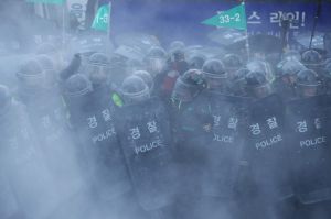 South Korean police officers are shrouded in smoke from a fire extinguisher, discharged by a supporter of former South ...