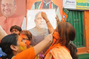 Bharatiya Janata party supporters hold up a poster of prime minister Narendra Modi as the party achieves a historic victory in the Uttar Pradesh state elections.