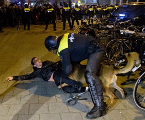 A Dutch riot policeman tries to get his dog to let go of a man after riots broke out during a pro Erdogan demonstration at the Turkish consulate in Rotterdam, Netherlands, Sunday, March 12, 2017.