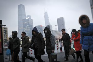 In this Feb. 21, 2017 photo, commuters, some wearing masks, walk to a subway station to a subway station during the evening rush hour in Beijing. Yet the city’s average reading of the tiny particulate matter PM2.5 - considered a good gauge of air pollution - is still seven times what the World Health Organization considers safe.