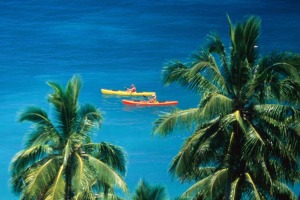 Two women kayak along the Fijian coastline.