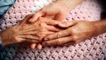 A woman's hand holding an elderly patient