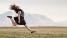 A woman jumping for joy in a field of grass.