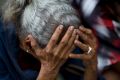 A woman holds her head as she waits in line outside a supermarket to buy food in Caracas, Venezuela. 