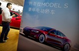 Visitors look at a Tesla Model S electric car on display at the Beijing International Automotive Exhibition in Beijing ...