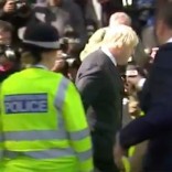 Police escort Boris Johnson past booing protesters outside his London home