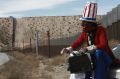 A protester dressed as a diabolical version of Uncle Sam holds a suitcase full of money at the US border fence in Ciudad ...