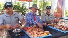 Bill Byrne (centre) eating prawns with Morgan's Seafood employees