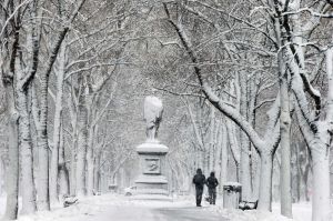 People walk beneath snow-covered trees on the Commonwealth Avenue Mall during a winter storm, in the Back Bay ...